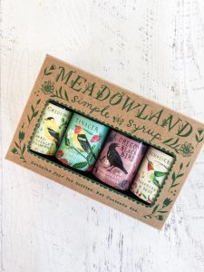 A box set of Meadowland Simple Syrup bottles featuring four colorful bird-themed designs on the labels. Perfect for summer essentials or a dinner party, the box is labeled "Contains four, two ounce bottles, use creatively!".