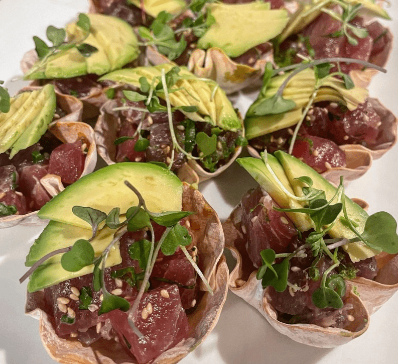 Small cups made of crispy wonton wrappers, filled with diced raw tuna, sliced avocado, microgreens, and sesame seeds on display showcase the culinary artistry taught by Chef Marissa Finch at Renton Technical College.