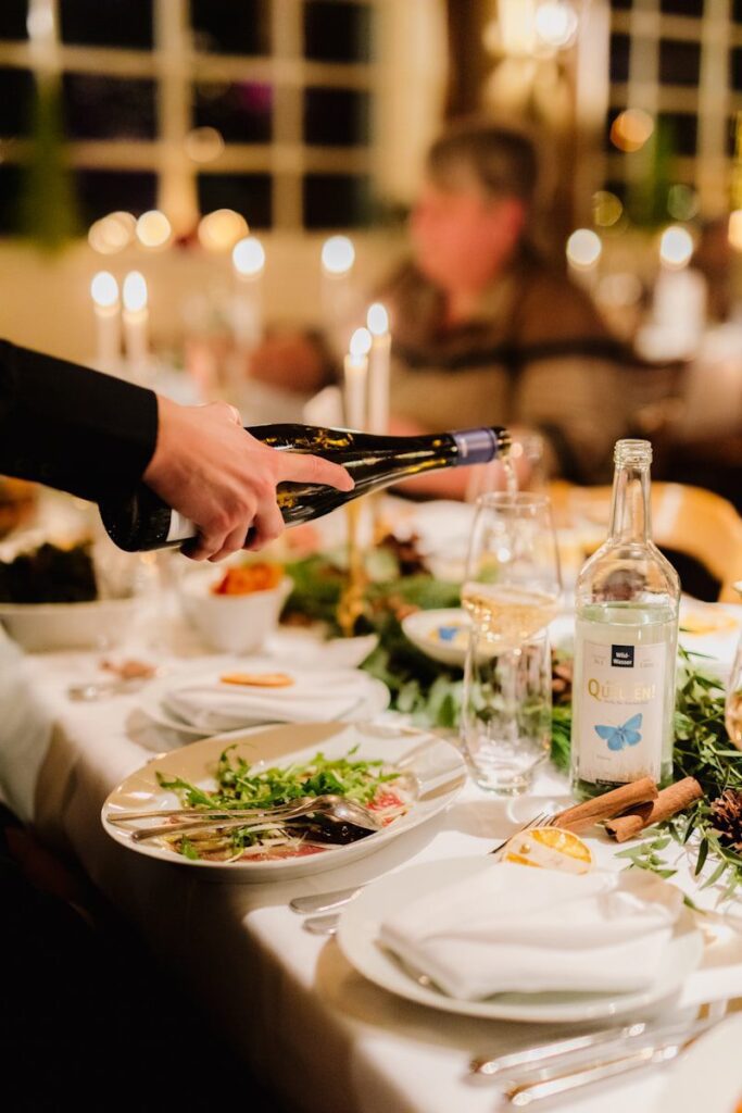 a person pouring wine into a glass at a dinner table