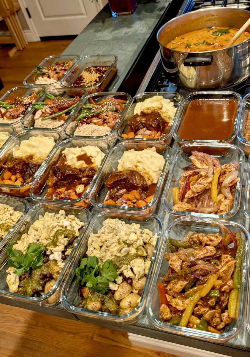 Glass meal prep containers filled with various cooked dishes, including vegetables, proteins, and sauces, arranged on a kitchen counter highlight the convenience of having a tacoma wa personal chef