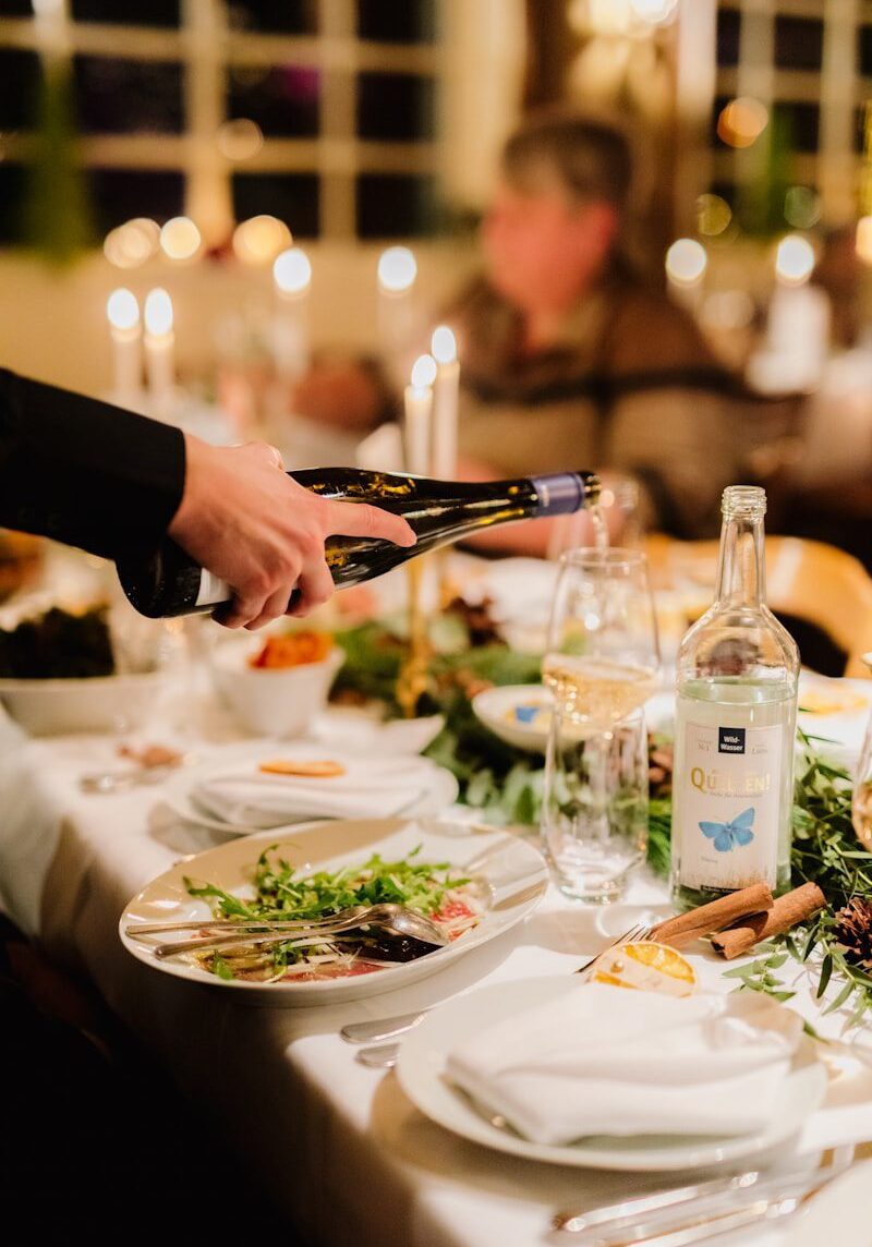 a person pouring wine into a glass at a dinner table